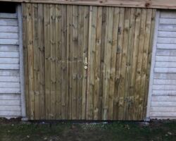 Dubbele schuifdeur aan betonnen tuinhuis.